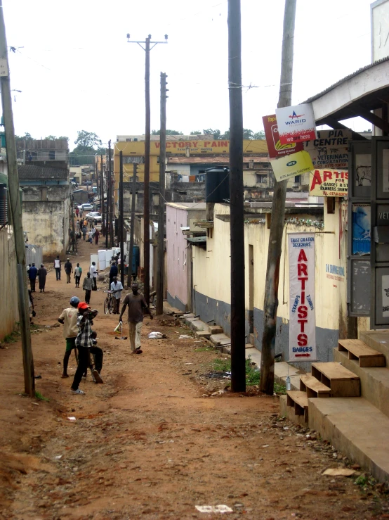 people are walking down a dirt path in an alley way