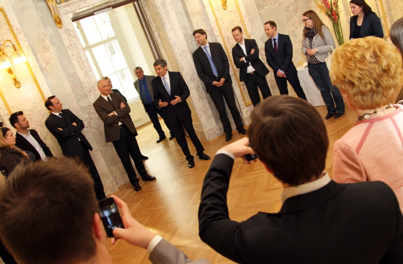 people in suits taking pictures and standing behind a man