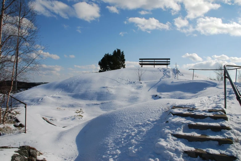 there is a bench on top of a snowy hill