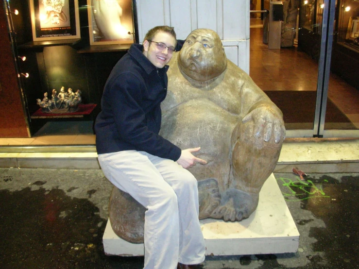 a man kneeling down next to a statue of a bear