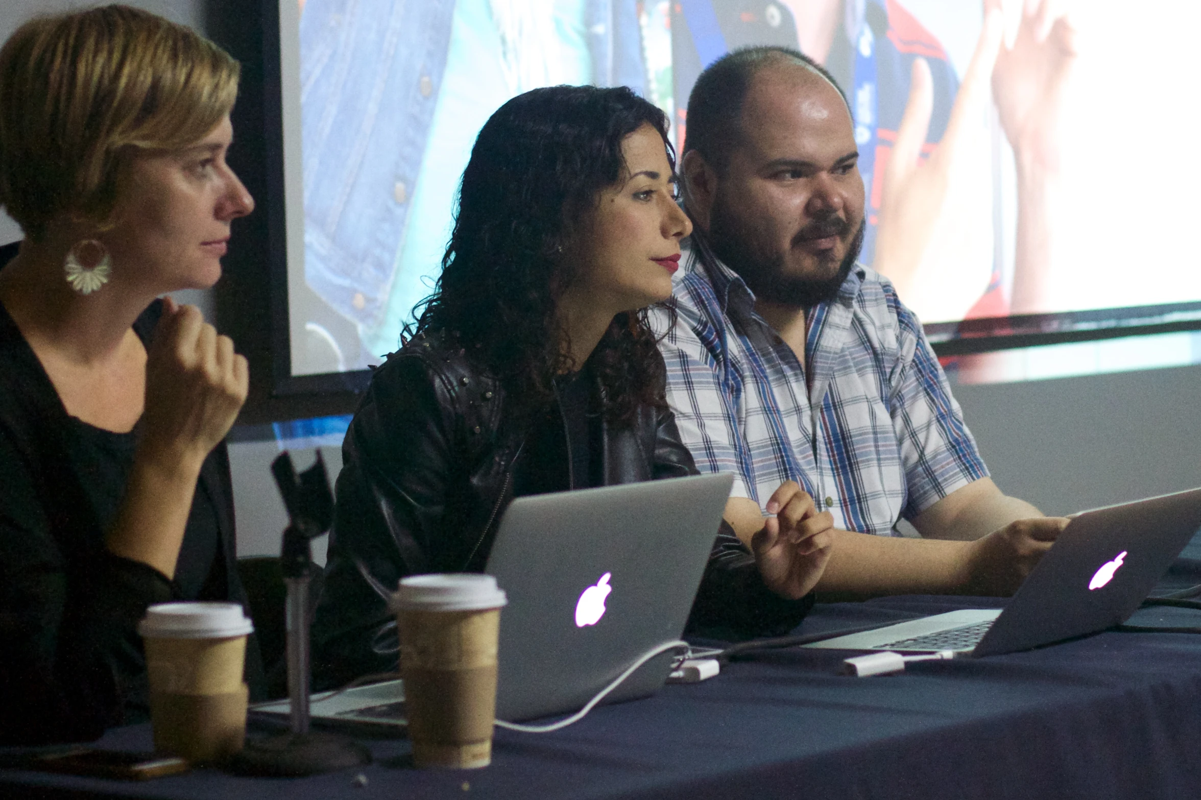 three people at a table talking and working