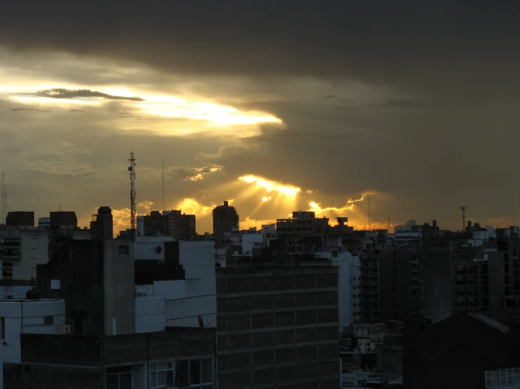 the sun setting over a city with clouds