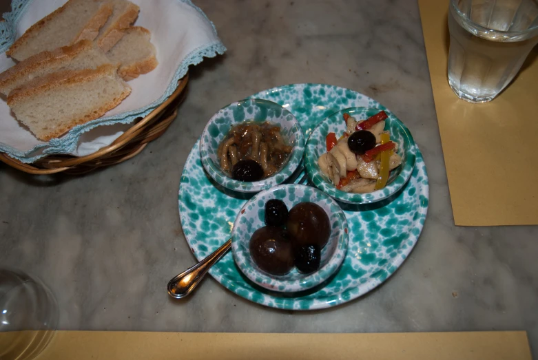 a small blue plate with two plates of fruit, bread and coffee