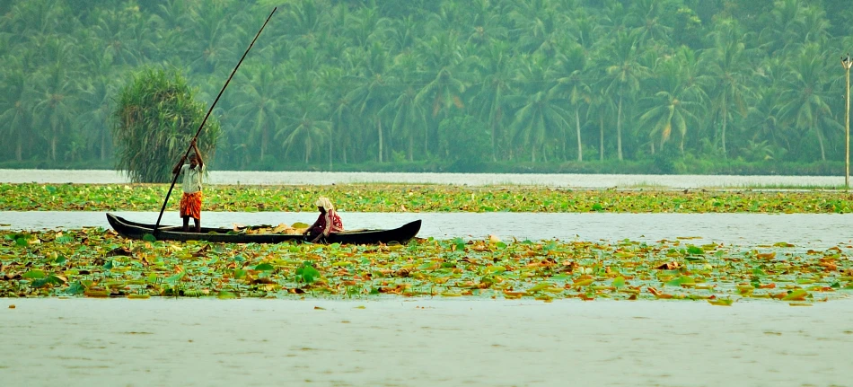 two people standing in a small boat on the water