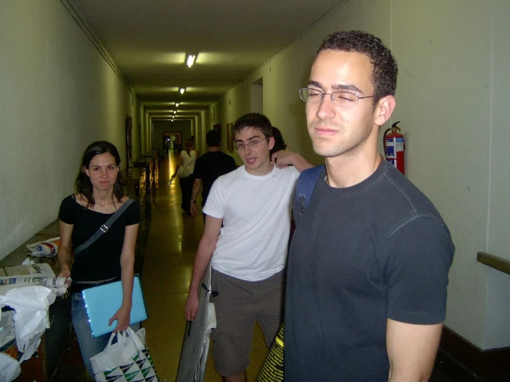 three people are standing in a corridor with two of them wearing glasses