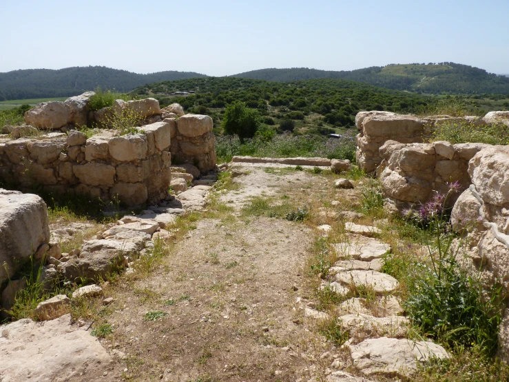 an old stone building with grass and bushes around it