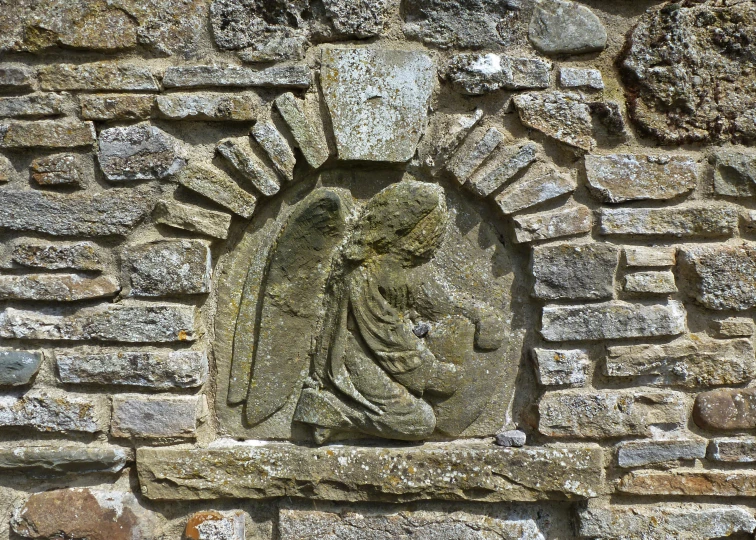 a stone angel is embedded in an old brick wall