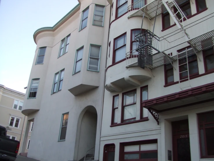 two apartment buildings on a corner and the second story is white with red trim and doors