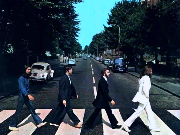 the beatles walk across an asphalt road in a street scene