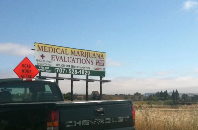 a black truck is parked in front of a medical marijuana sign