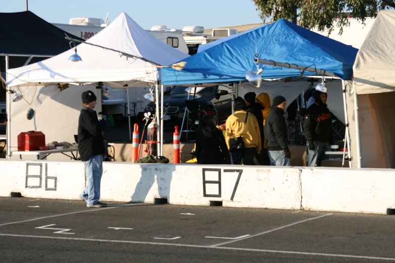 people stand under a tent in a parking lot