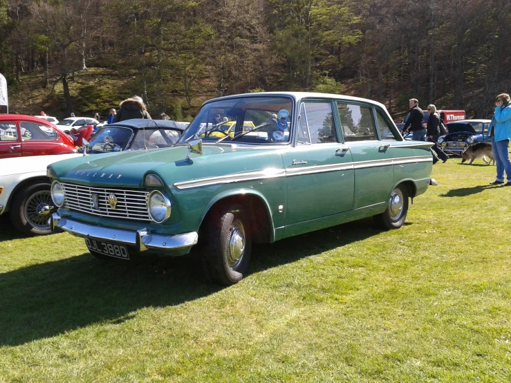 an old blue station wagon sitting in the grass