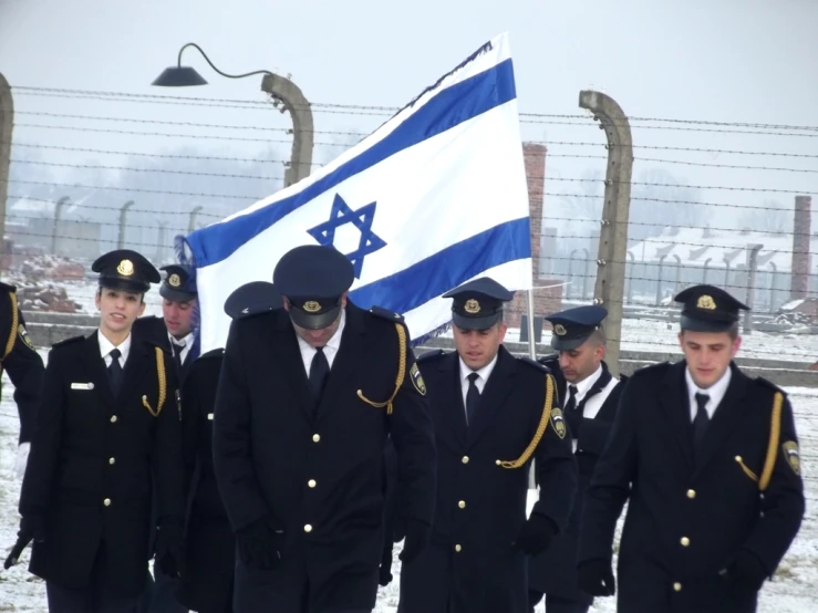 a group of israeli men in uniform holding a flag