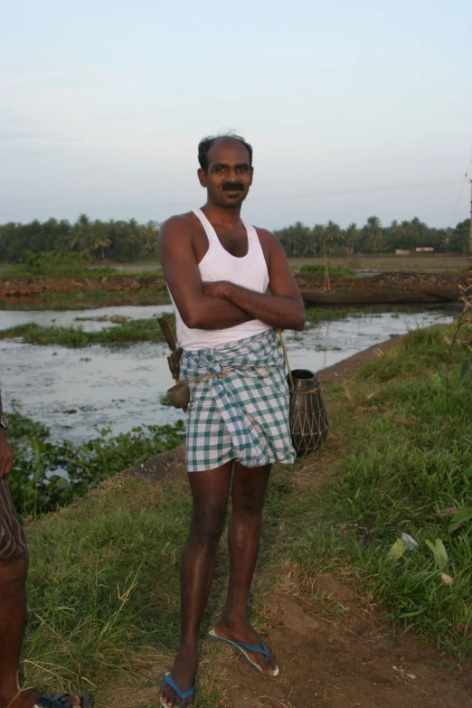 a man wearing shorts standing near a river