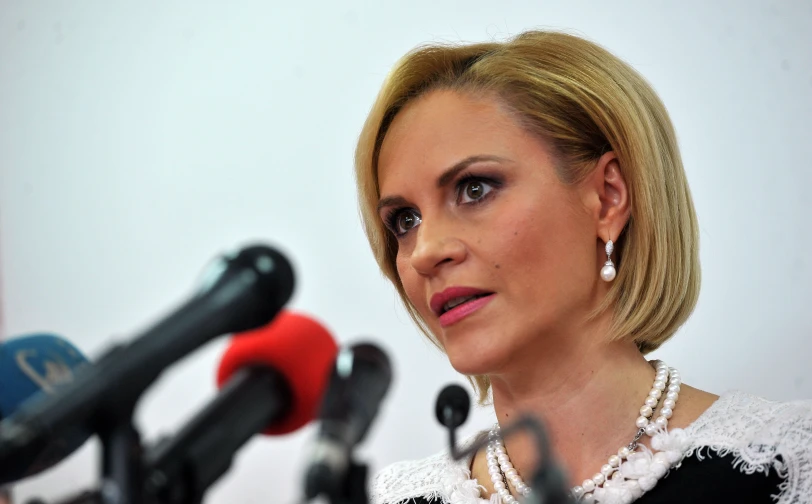 a woman with short hair standing behind a microphone