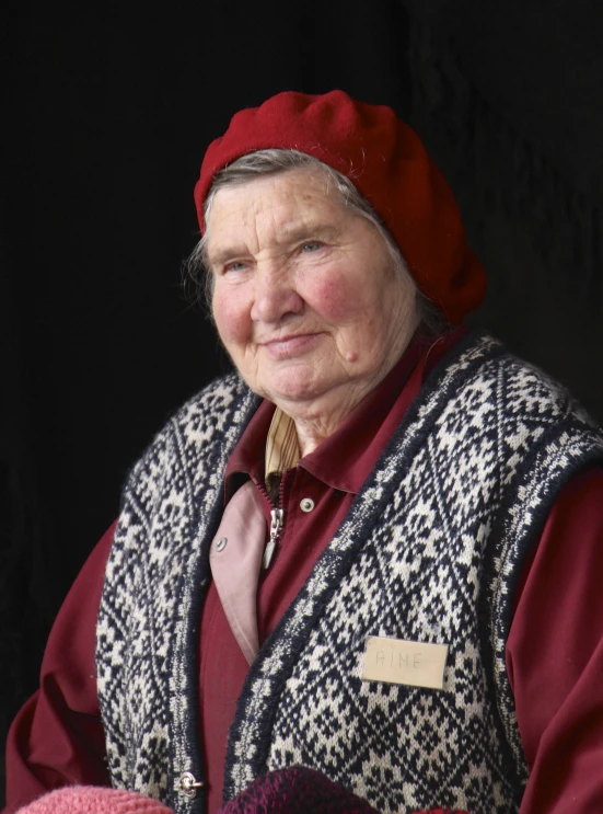 an old woman in a red hat and jacket looks up