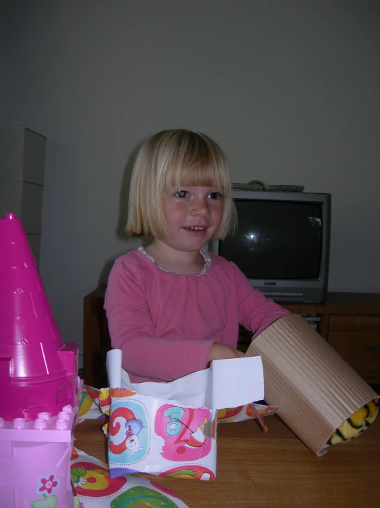 a little girl sitting at a table in front of a tv