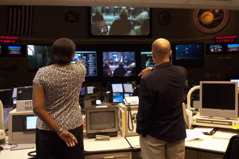 a man and woman standing in front of monitors