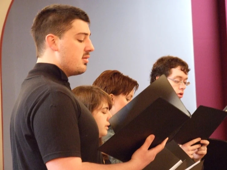 a group of young men singing with sheet music