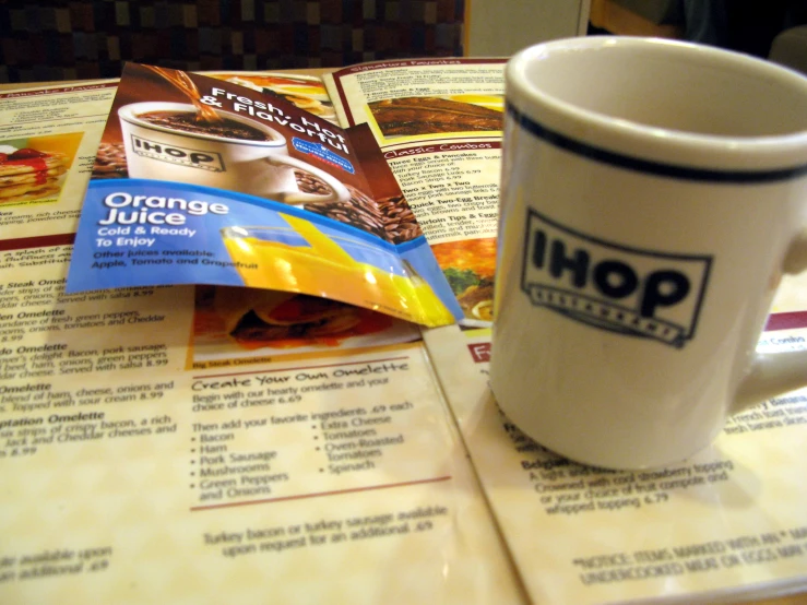 a coffee cup sitting next to a magazine on top of a table