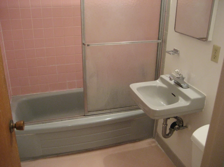 the bathroom has pink tile on the walls and floor