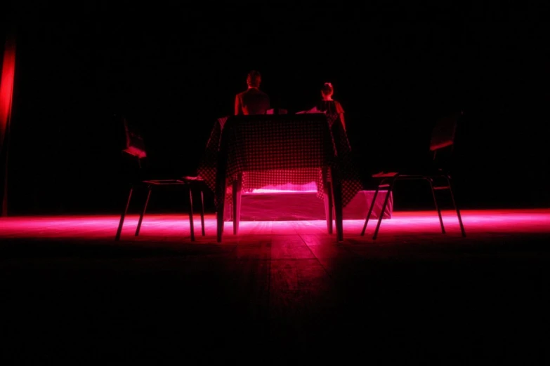 two people sitting at a table in a dark room