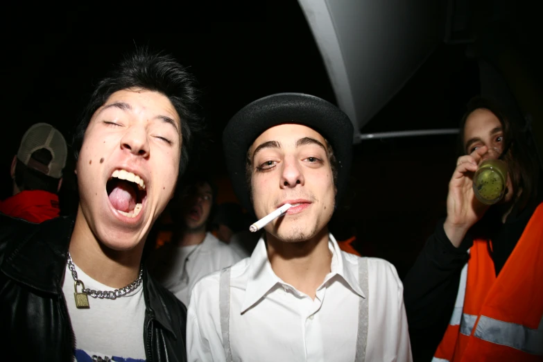 two young men are smoking and laughing while posing for a picture