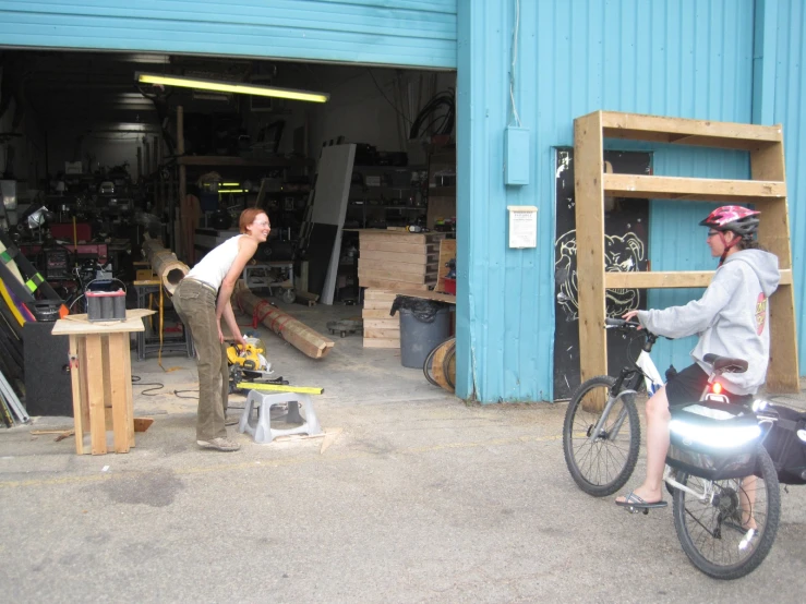 two men working inside a garage while a man talks to another person