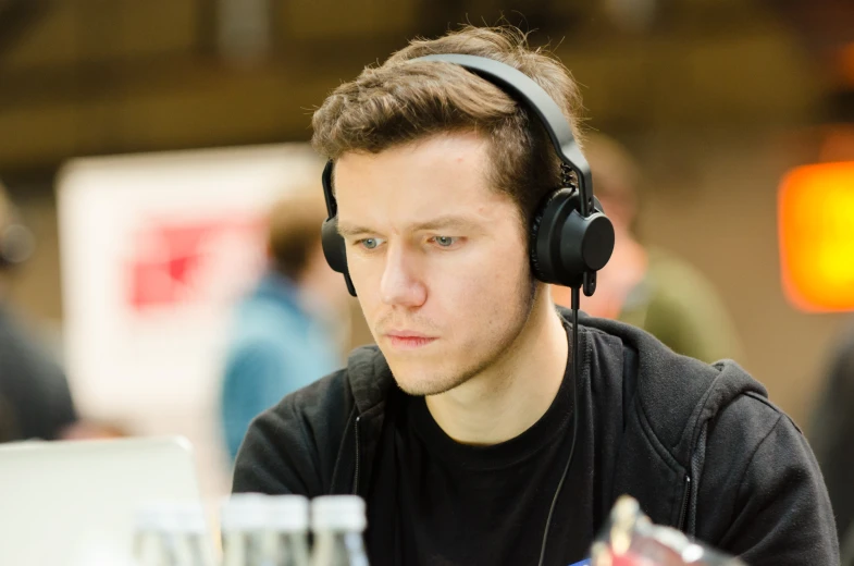 young man with headphones sitting at a table and looking down