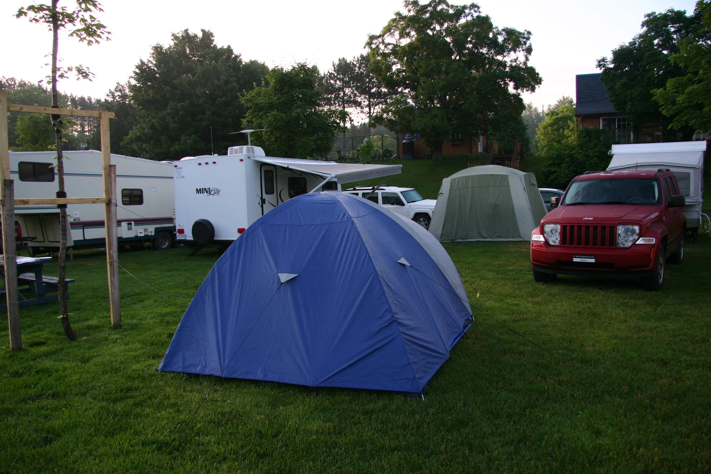 a tent and camper trailers with trees in the background