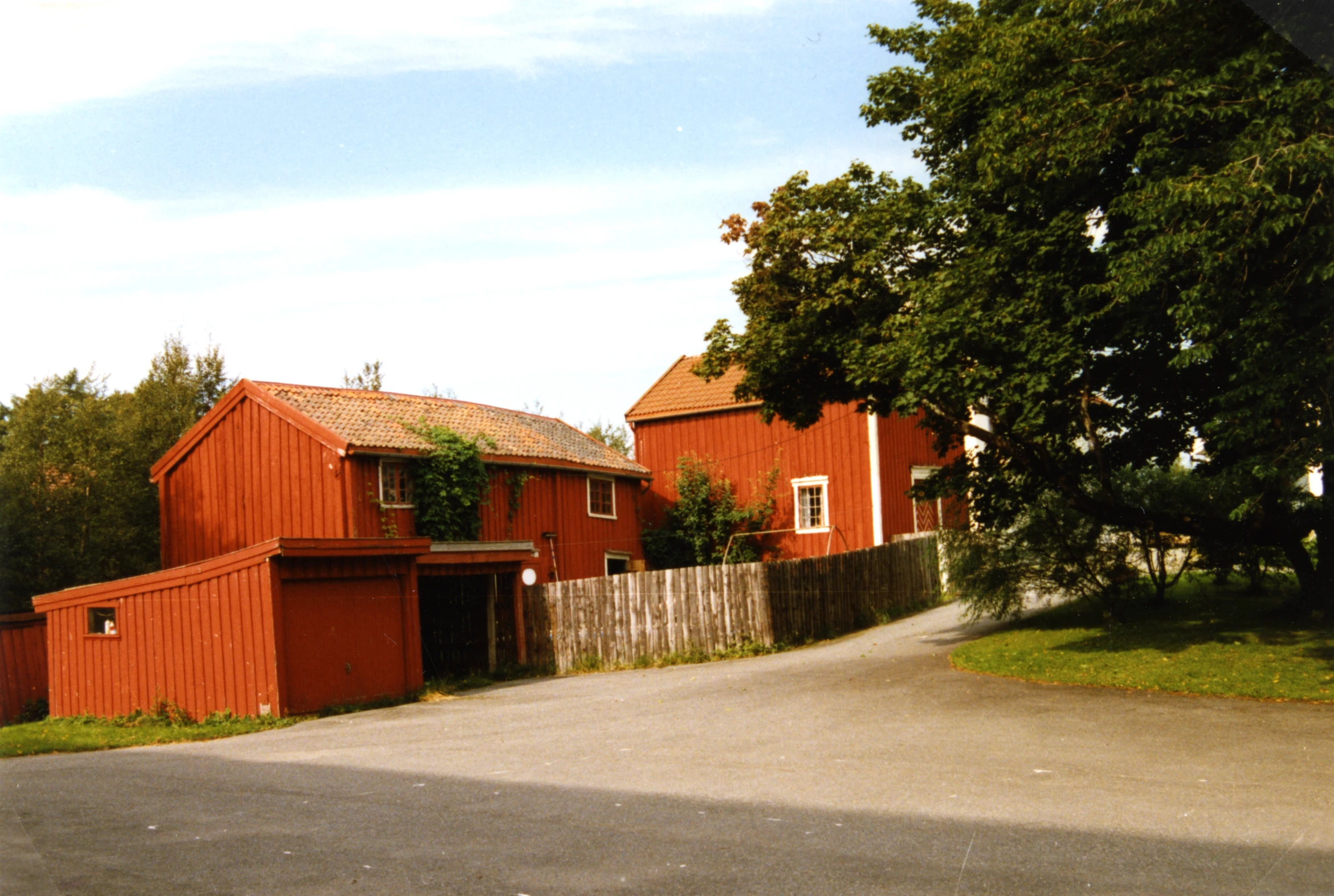 a long red house sitting in the middle of a green yard