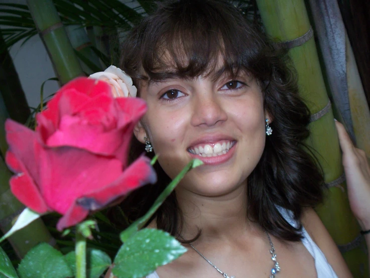 a woman is holding a flower while smiling
