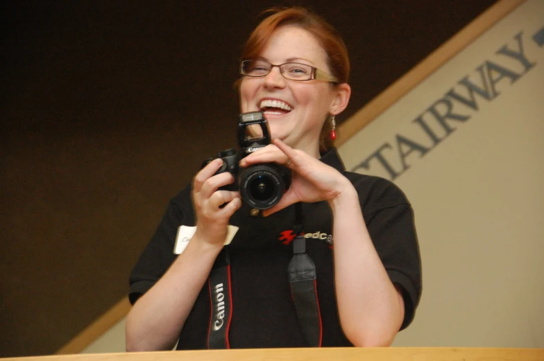 a woman smiles as she holds her camera and laughs