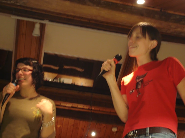 a woman in red shirt holding a microphone standing next to another woman