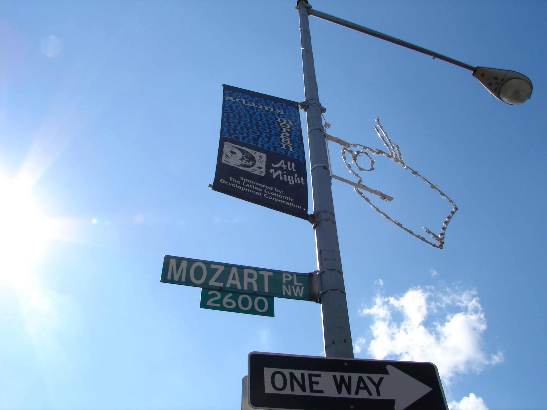 the sun shining on a street light with two street signs