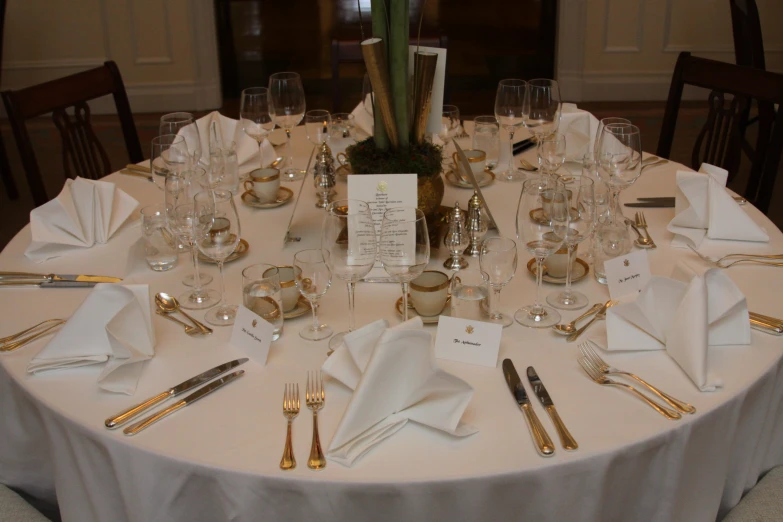 a formal table setting with golden cutlery and dishes