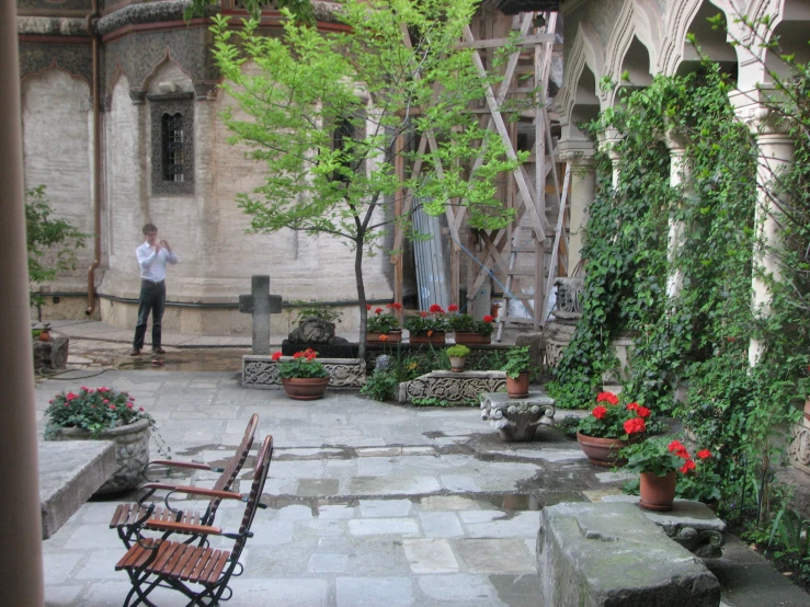 a man in shirt standing on patio surrounded by flowers