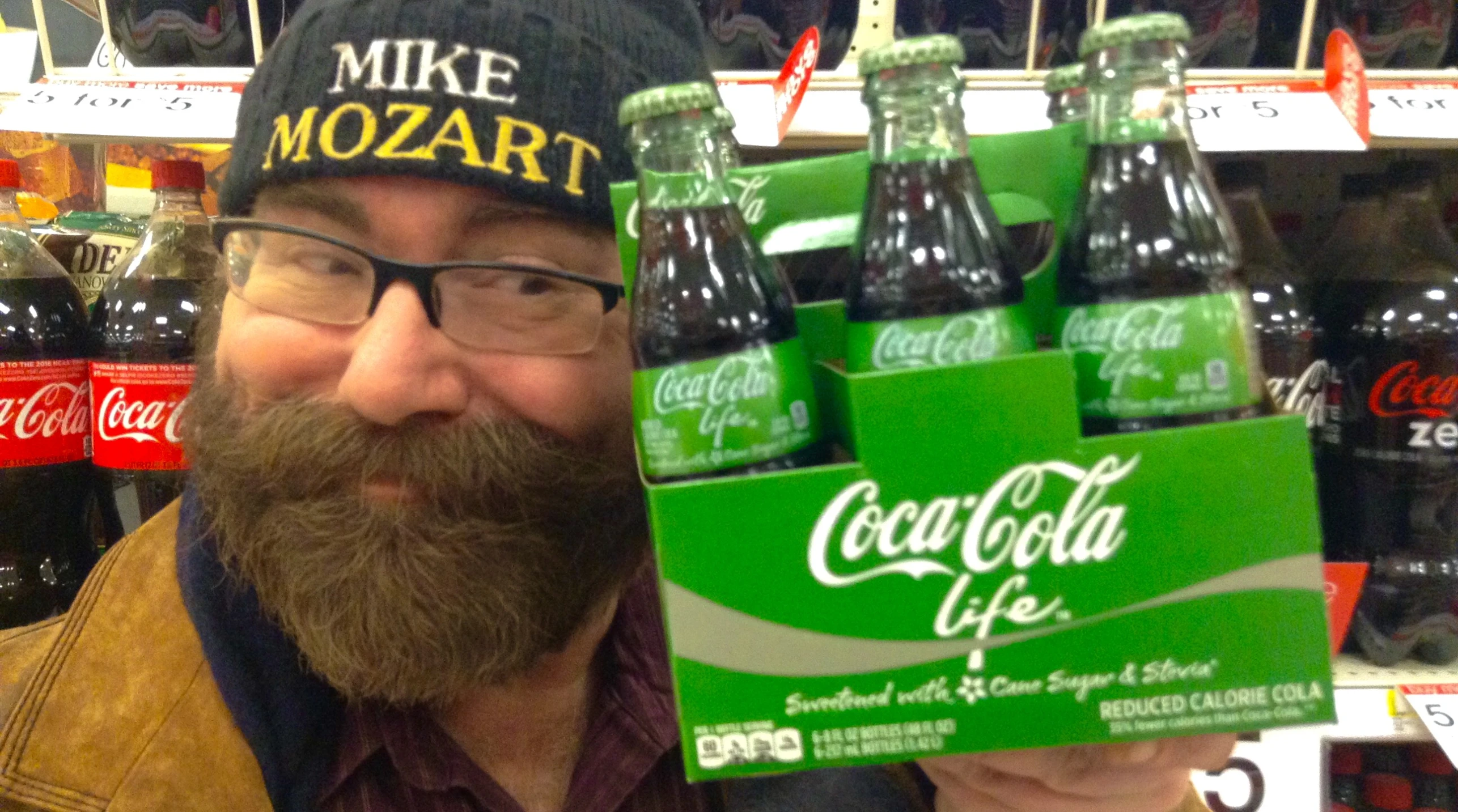 a man with a beard holds up a case of cola