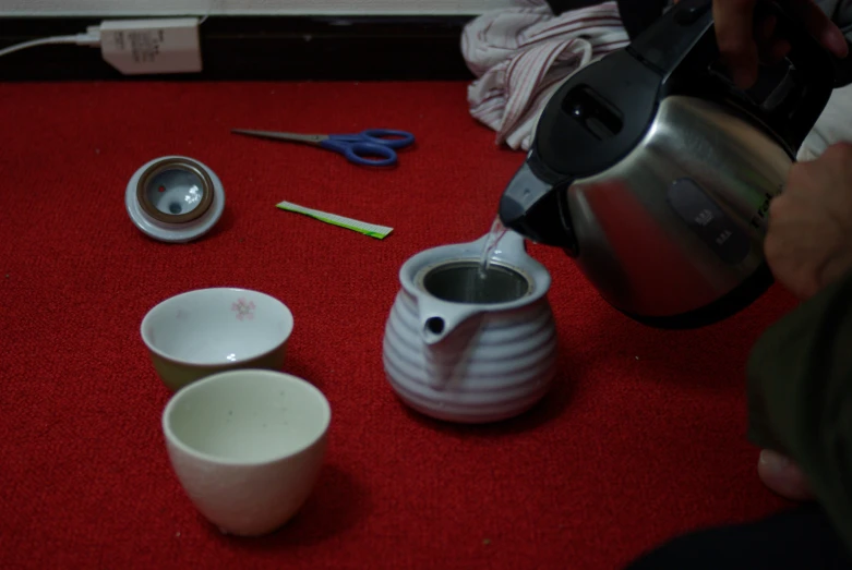 coffee pot being filled with liquid next to small measuring cup