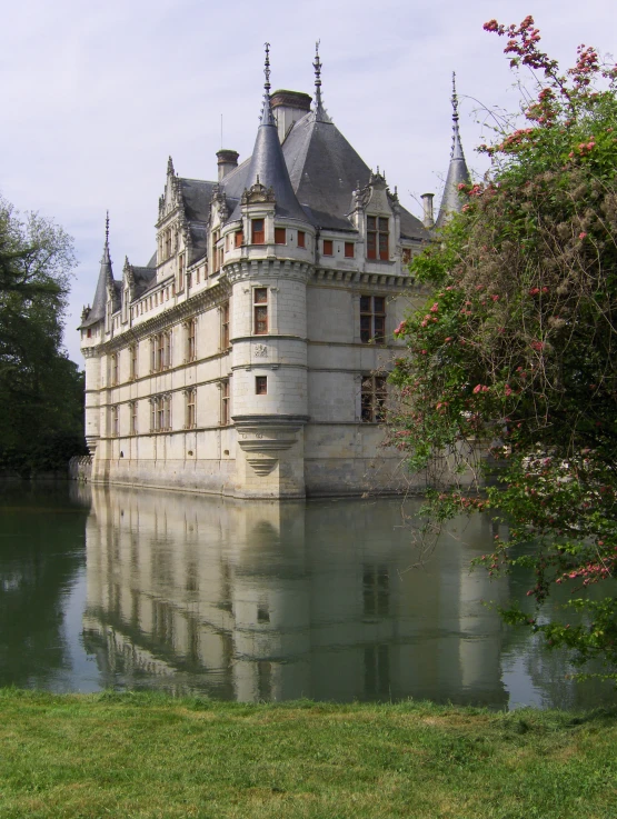 the castle sits over water as it reflects in the grass