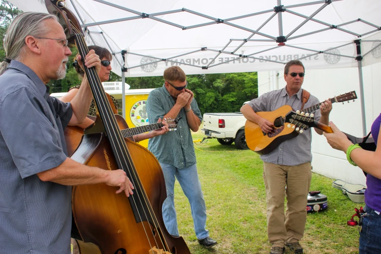 four men standing around a group playing music