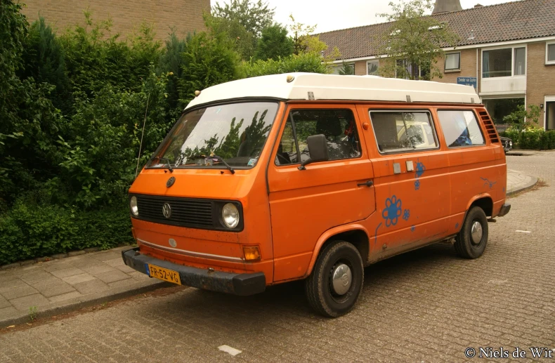 an orange van parked in the driveway near trees