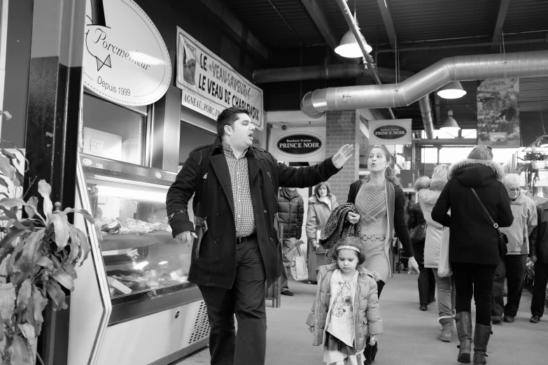 a man holds out his hand to a small child as people walk through the center