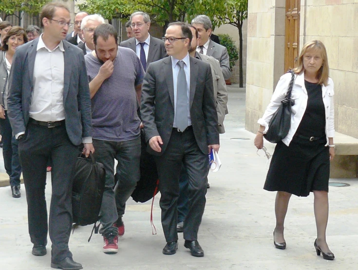 several people in suits and ties walking down the street