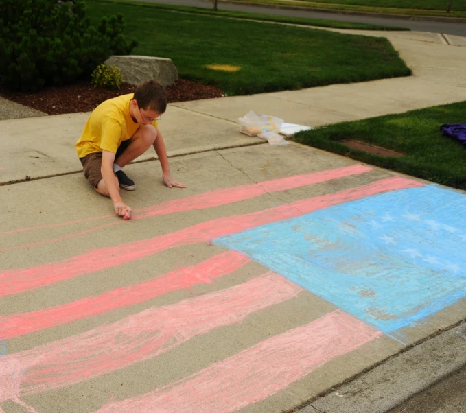 the little boy is playing with crayons on the sidewalk