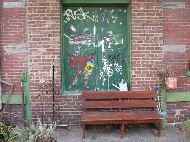 a wooden bench sitting on the ground near a brick wall