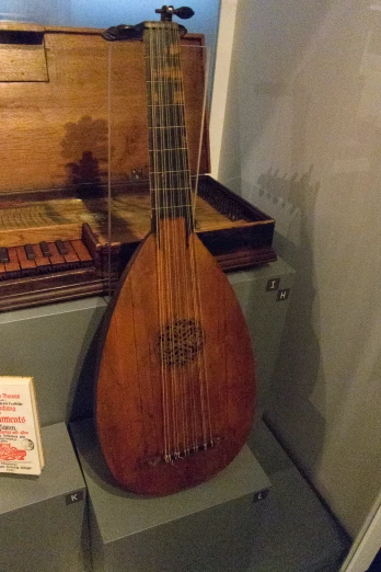 a brown ukulele on a stand next to a piano