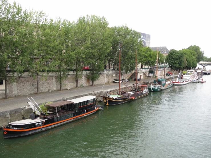 boats on the river next to the stone walls