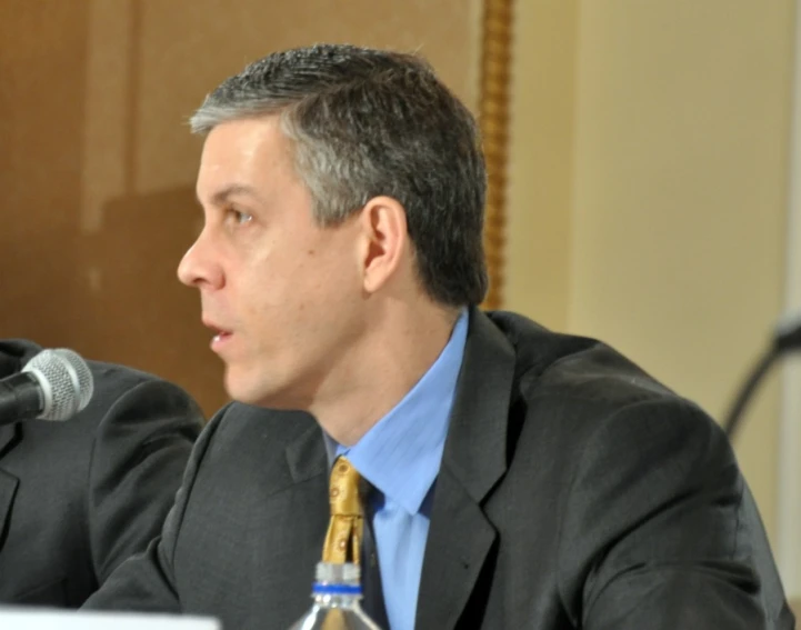 a man in a suit and tie talking into a microphone