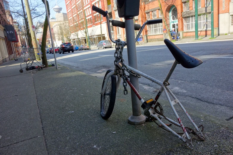 the bicycle is  to a parking meter on the sidewalk